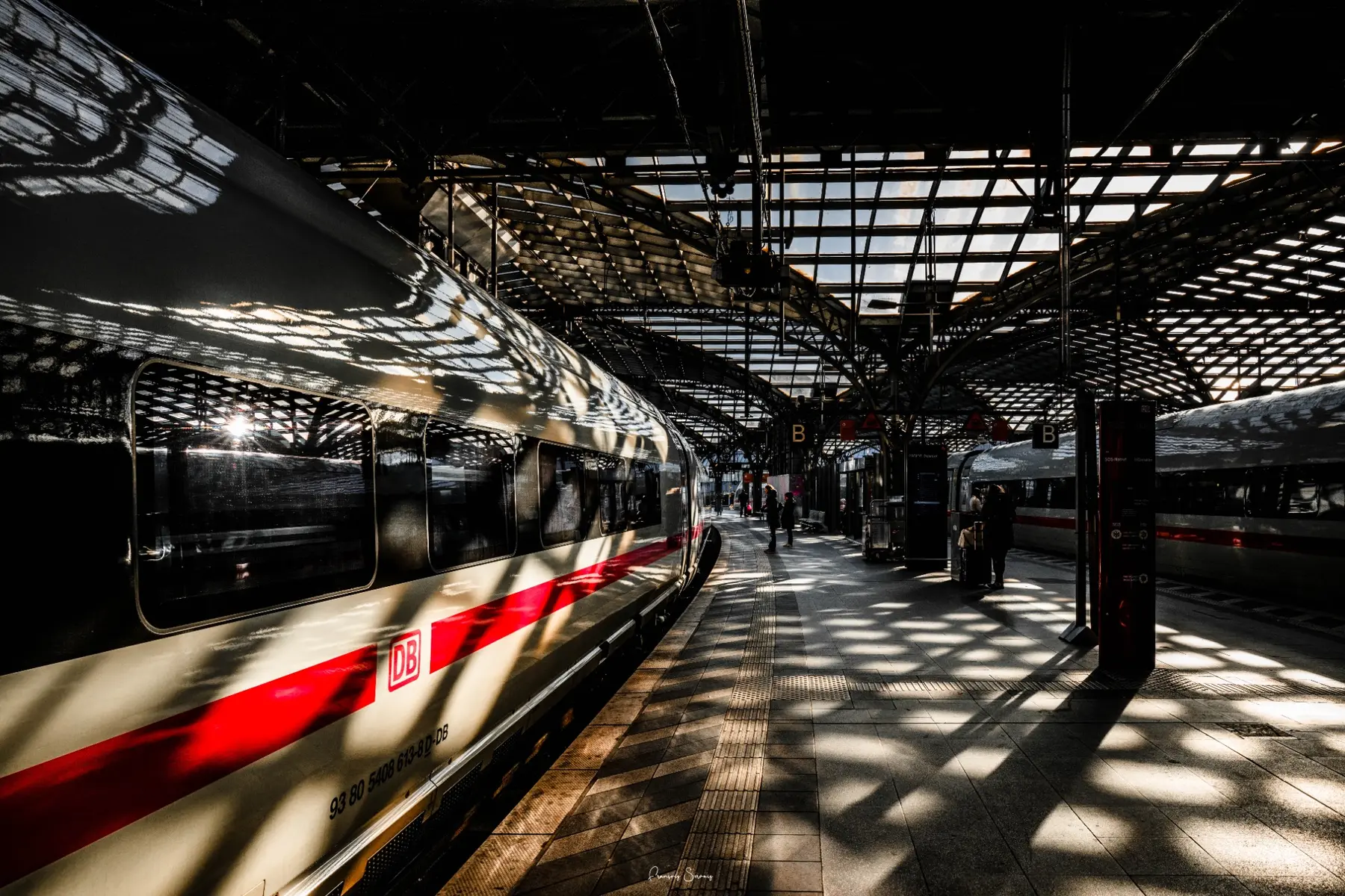 Voies et trains d’une gare traversés par des ombres géométriques