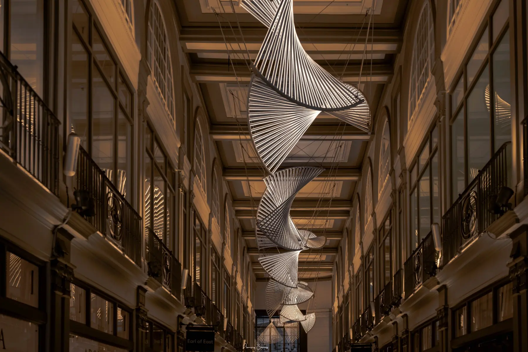 Passage intérieur chaleureux rythmé par une installation suspendue