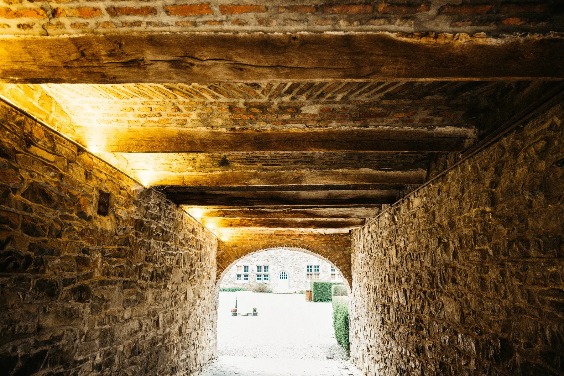Passage voûté en pierre menant vers une ouverture très lumineuse