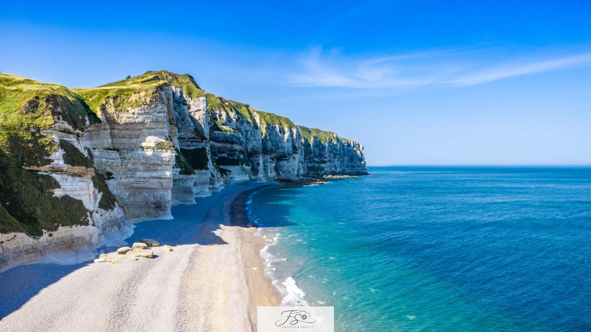 Grand large — falaise blanche bordée d’une mer bleue et d’une plage de galets