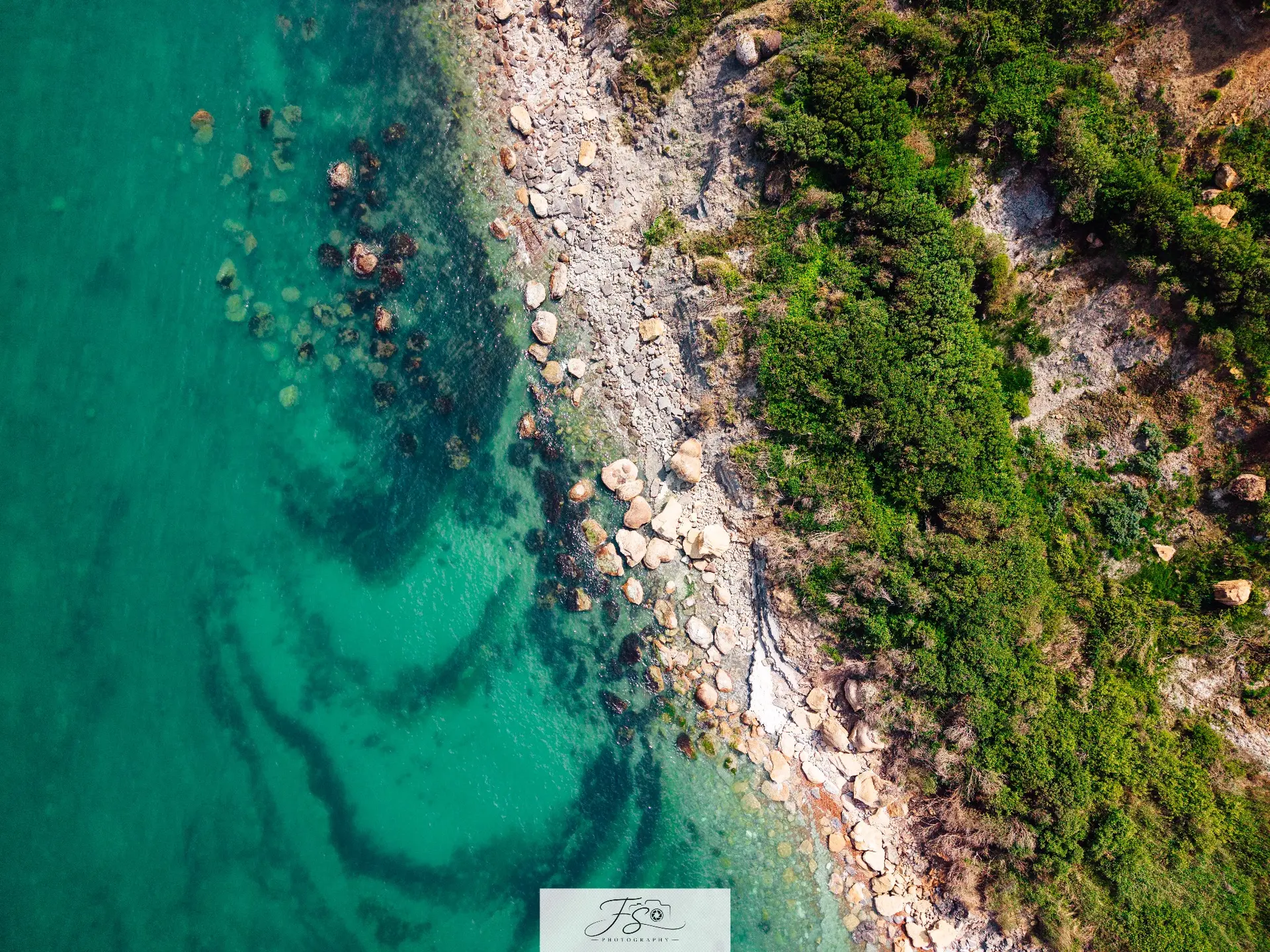 Rivage émeraude — rencontre verticale entre eau turquoise, galets et végétation