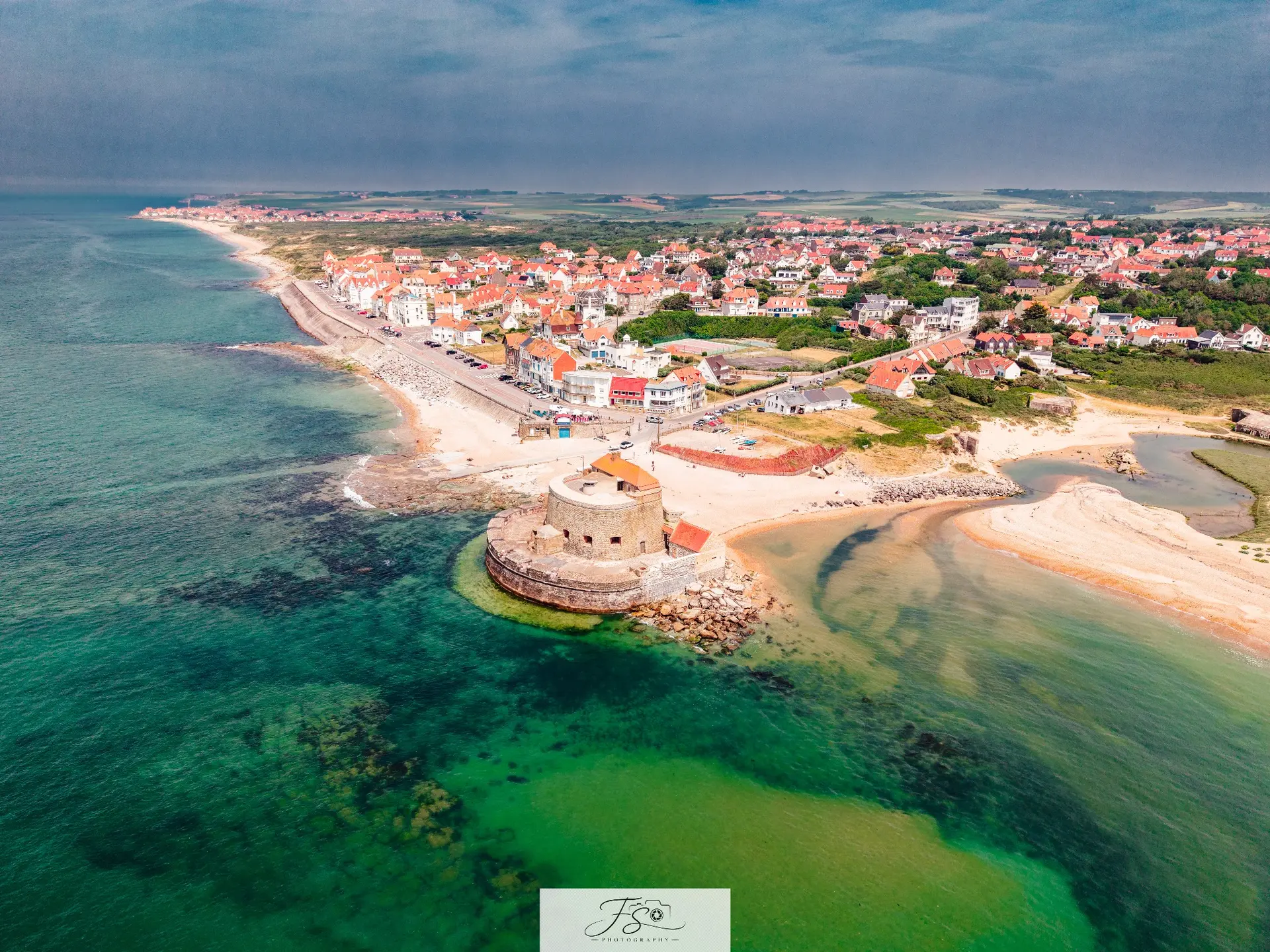 Le fort et la mer — fortification côtière et village baignés par une eau vert émeraude