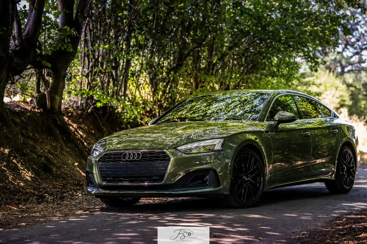 Audi A5 vert District photographiée sous les arbres