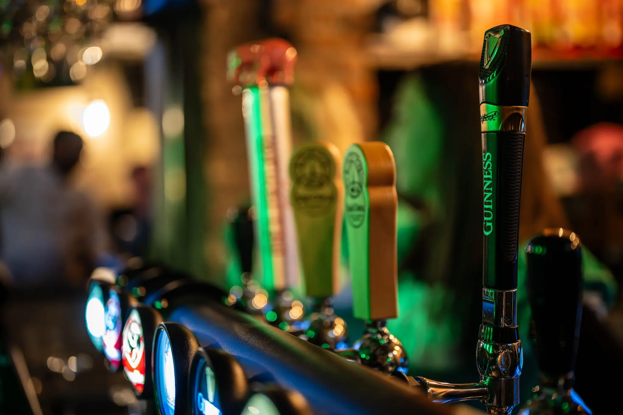Tireuses à bière baignées de lumière verte au bar Chez Marie