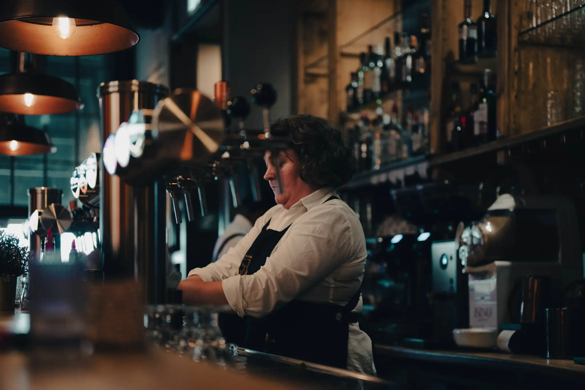 Professionnelle derrière le bar dans une ambiance chaleureuse