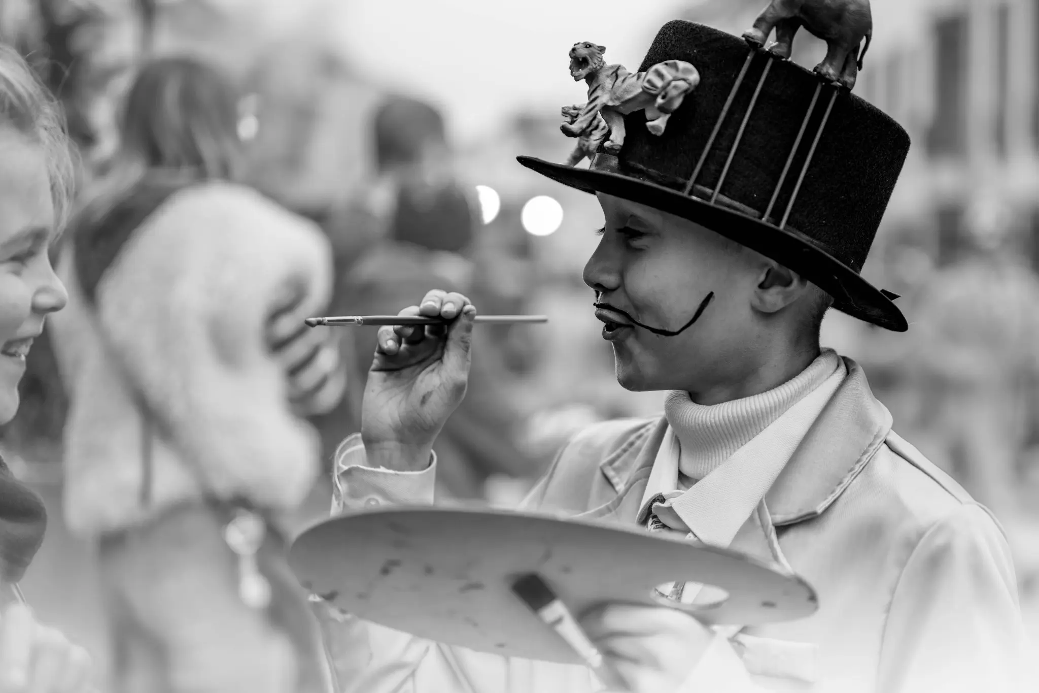 Participant costumé maquillant le visage d’un enfant pendant le Carnaval de Malmedy 2025