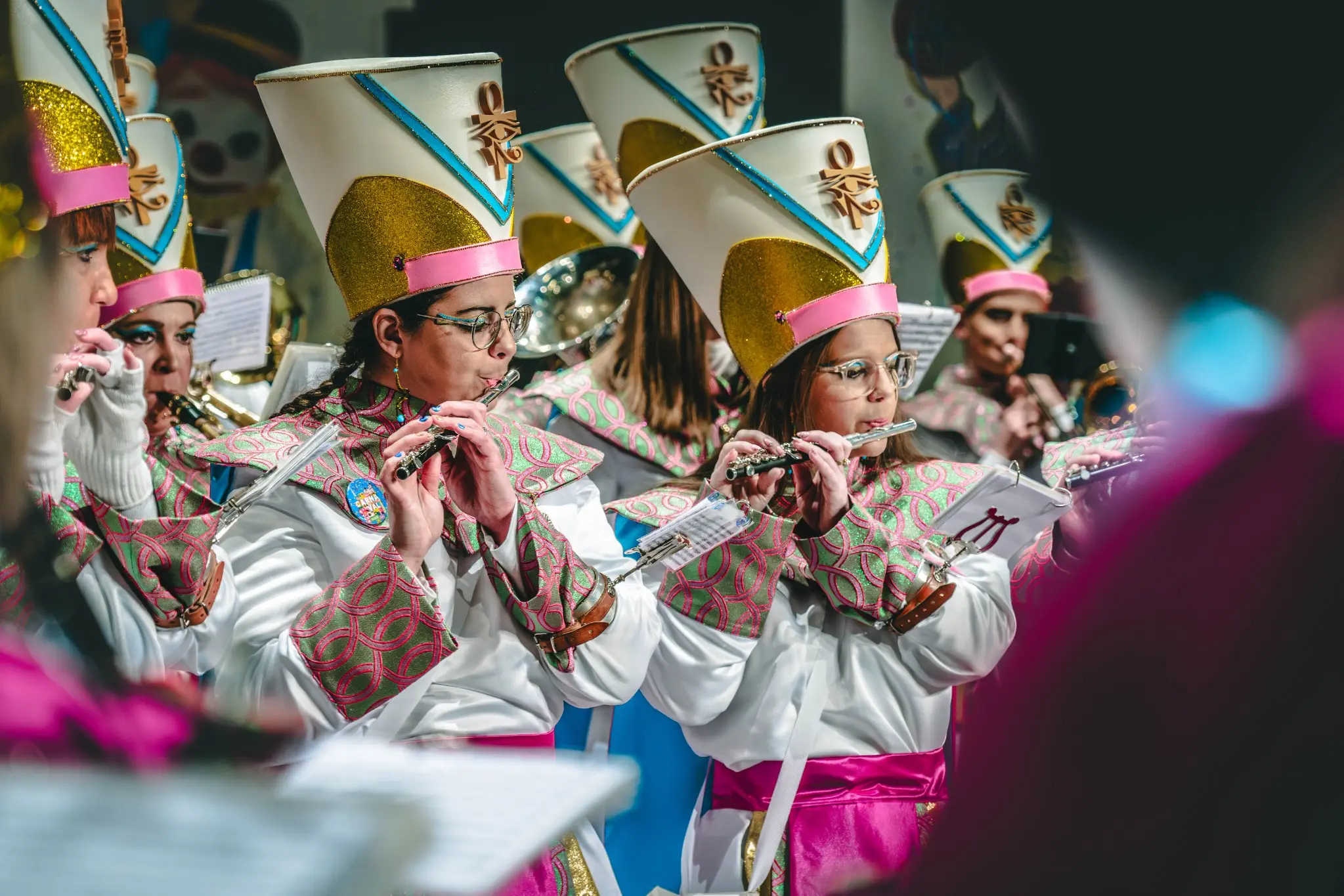Musiciennes en costumes blanc, rose et or jouant de la flûte au Carnaval de Malmedy 2025