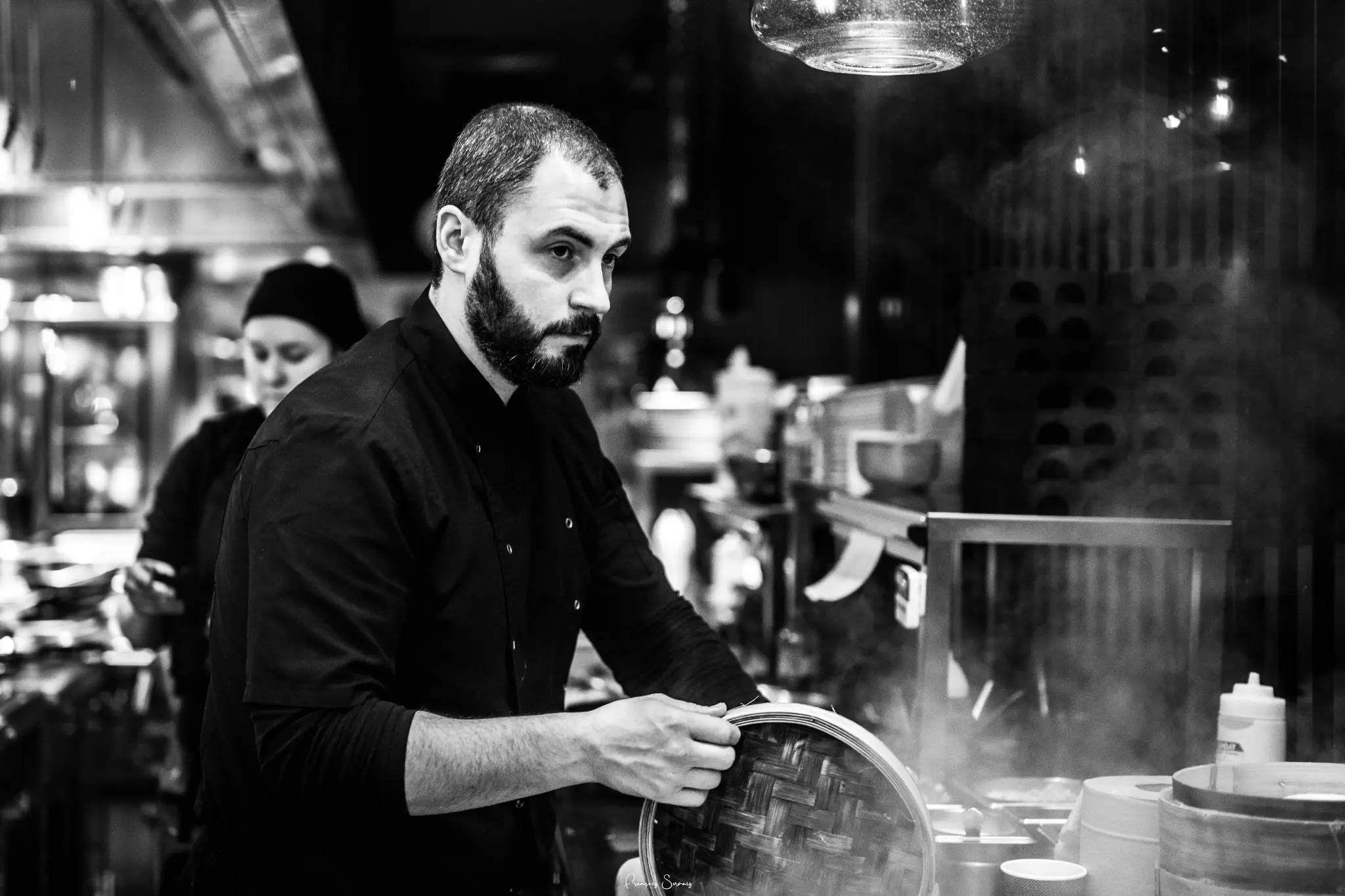 Chef concentré à son poste de travail, photographié à travers une vitre