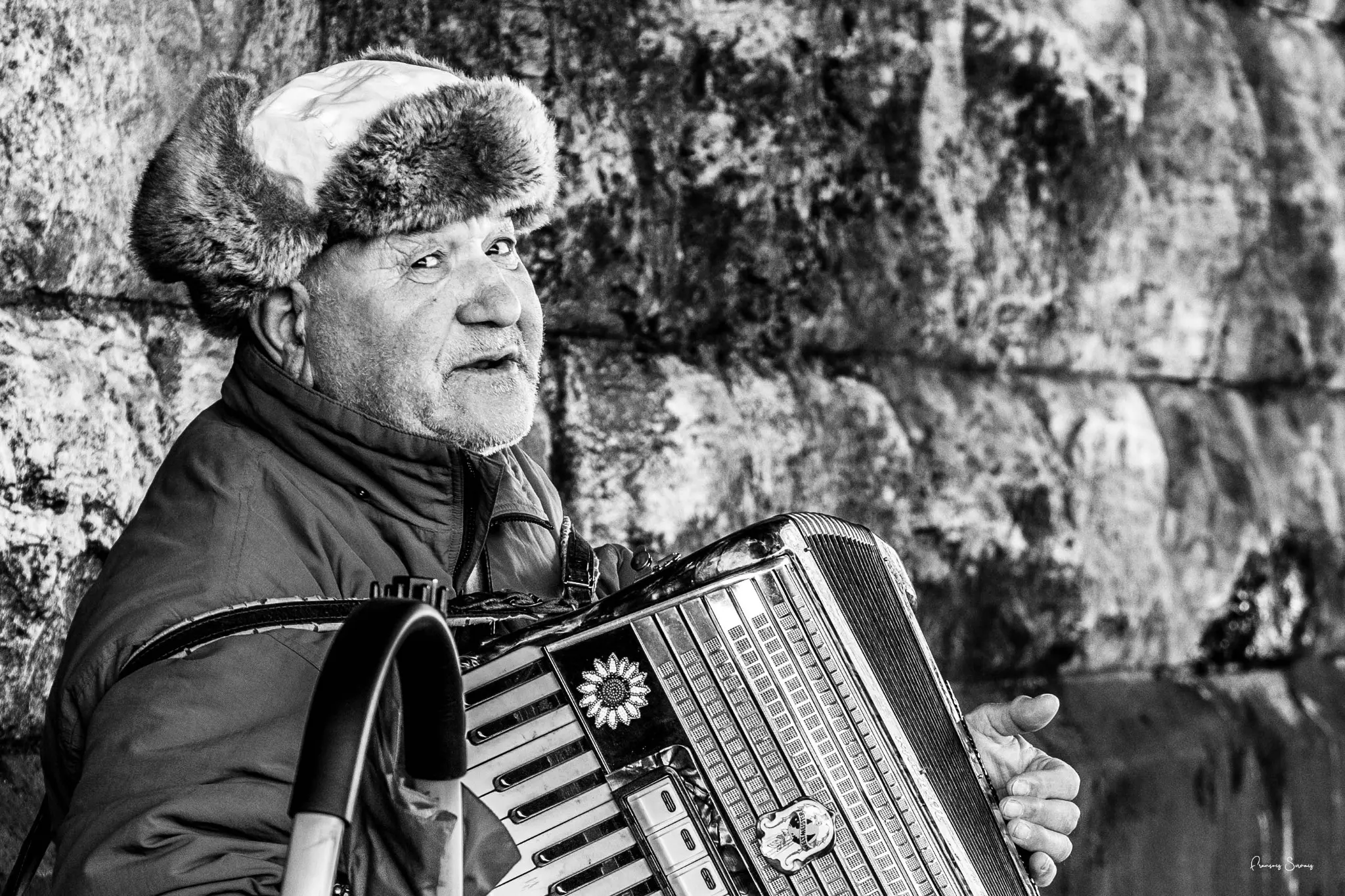 Portrait en noir et blanc d’un musicien coiffé d’un bonnet de fourrure avec son accordéon