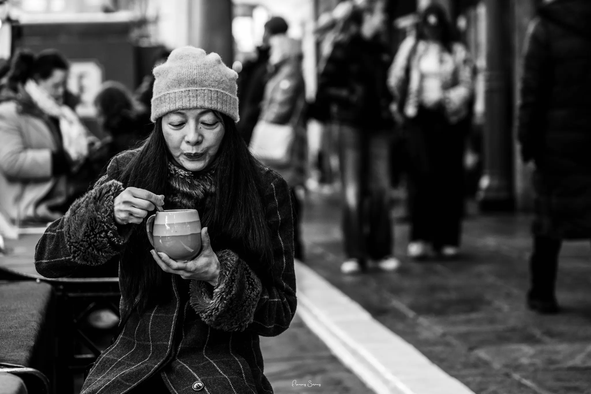 Femme coiffée d’un bonnet tenant une tasse chaude entre ses mains