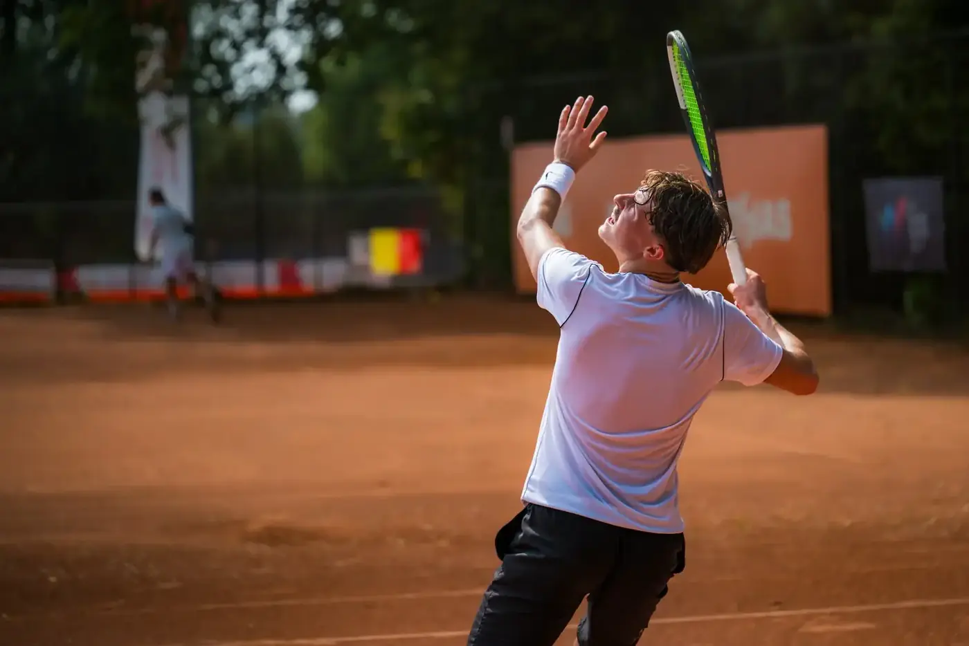 Joueur de tennis au lancer de balle pendant son service sur terre battue