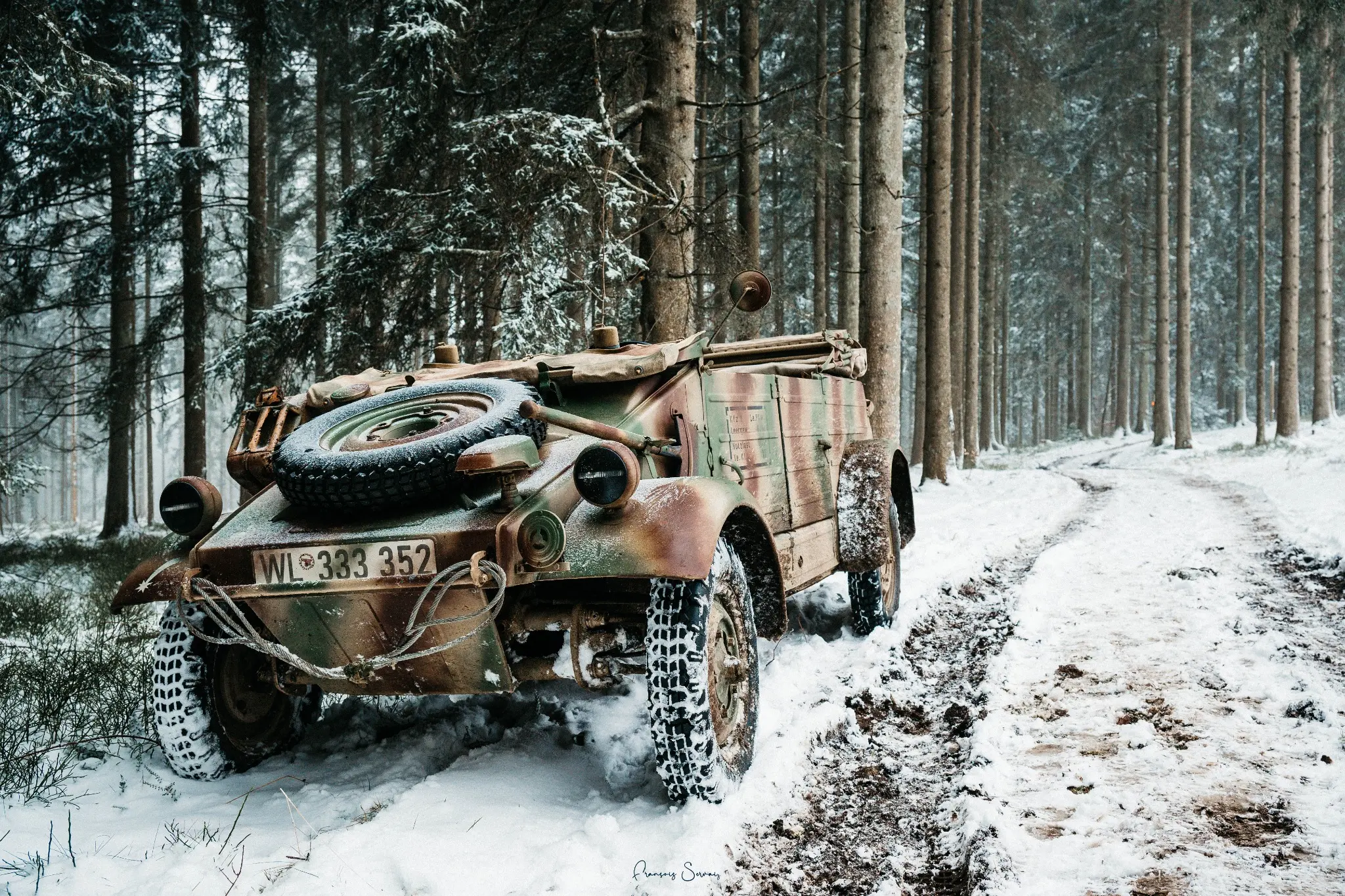 Véhicule militaire d’époque mis en scène dans une forêt enneigée lors de la reconstitution historique à Thirimont